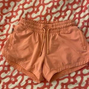 Athleta orange shorts with zipper pockets and back pocket